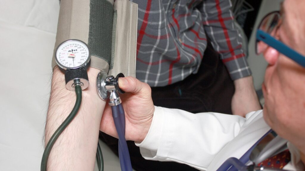 male doctor taking blood pressure of male patient